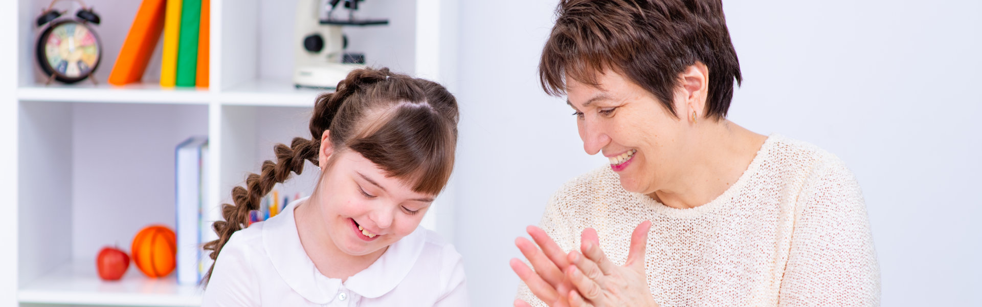 a woman smiling clapping her hands with a girl smiling